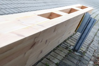 Das Foto zeigt eine Leitplanke aus Holz, die an einem Metallpfosten befestigt ist.
