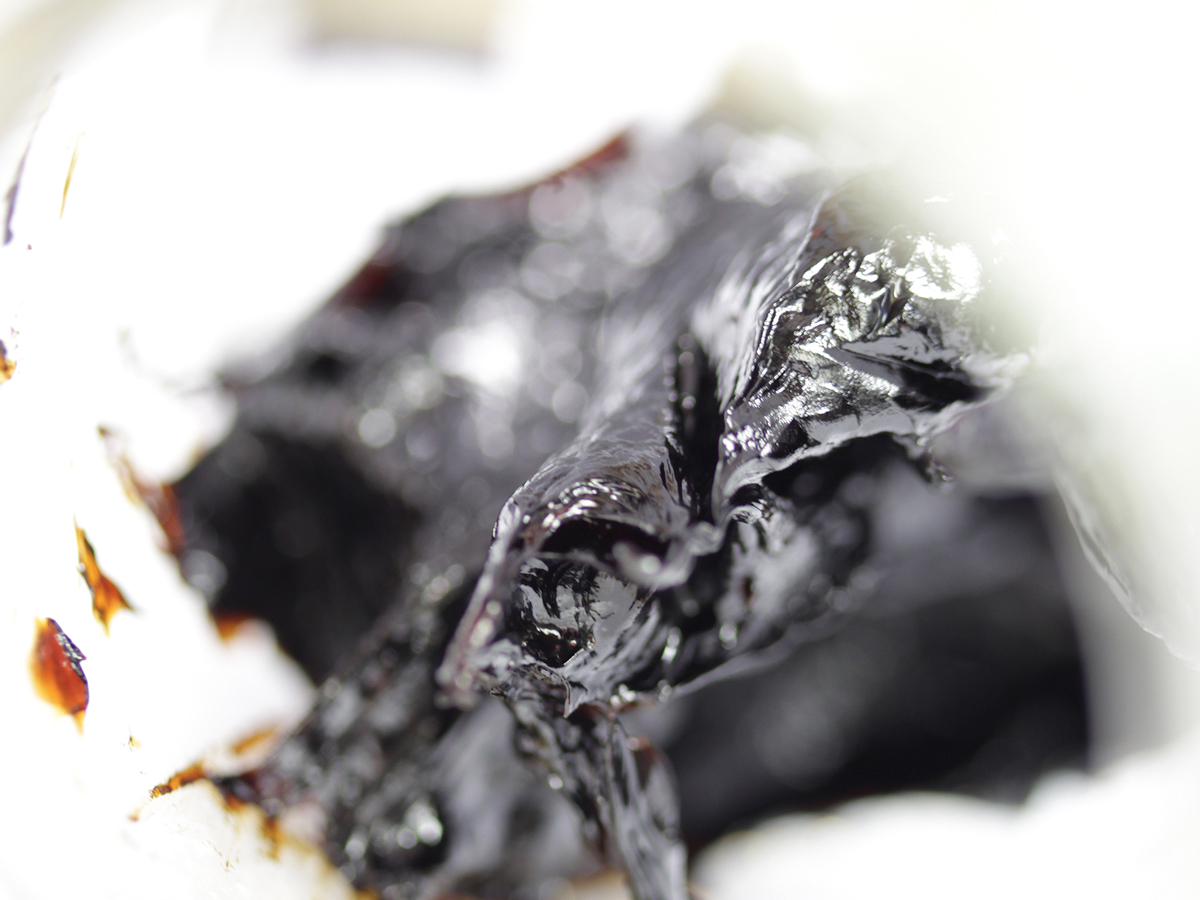 Nahaufnahme von einem schwarzbraunen Material mit pastöser Konsistenz.