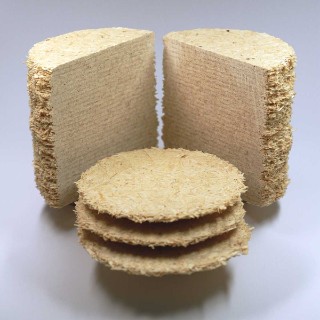 Im Hintergrund sieht man zwei Hälften eines zylindrischen Probekörpers, der mithilfe der additiven Fertigung aus Holzspänen hergestellt wurde. An der Schnittfläche kann man die Schichten erkennen. Im Vordergrund liegen drei kreisförmige Schichten, die zur Herstellung des Zylinders eingesetzt wurden