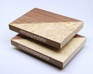 Das Foto zeigt zwei teilweise furnierte Spanplattenstücke, die nahezu identisch aussehen. Bei der oberen Platte (Altholz) sind einige Späne minimal dunkler. 