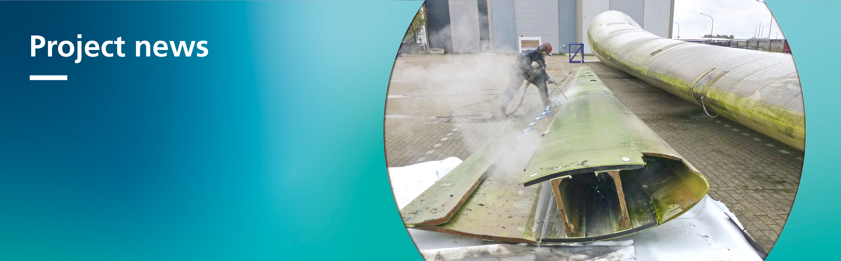 Das Foto zeigt ein aufgeschnittenes Windkraft-Rotorblatt, das innen größtenteils hohl ist. Die Schale ist im mittleren Bereich auf der ganzen Länge des Rotorblatts mit dunkelgrauem Material verstärkt.