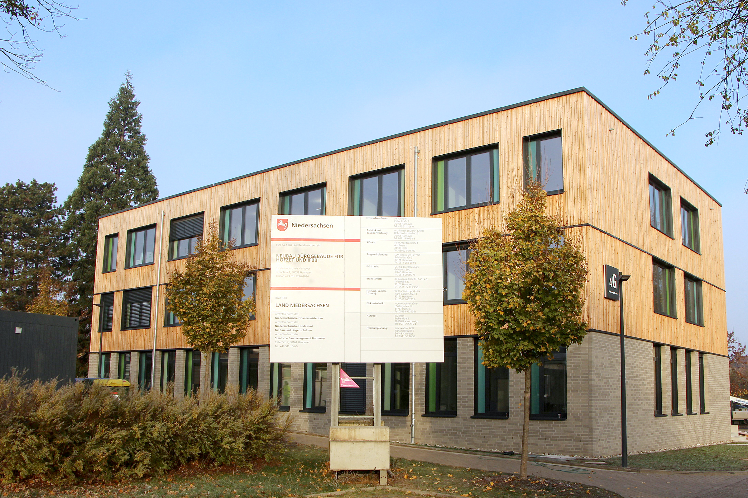 Das Foto zeigt ein dreistöckiges, modernes Bürogebäude mit einer Fassade aus Klinker und Holz.