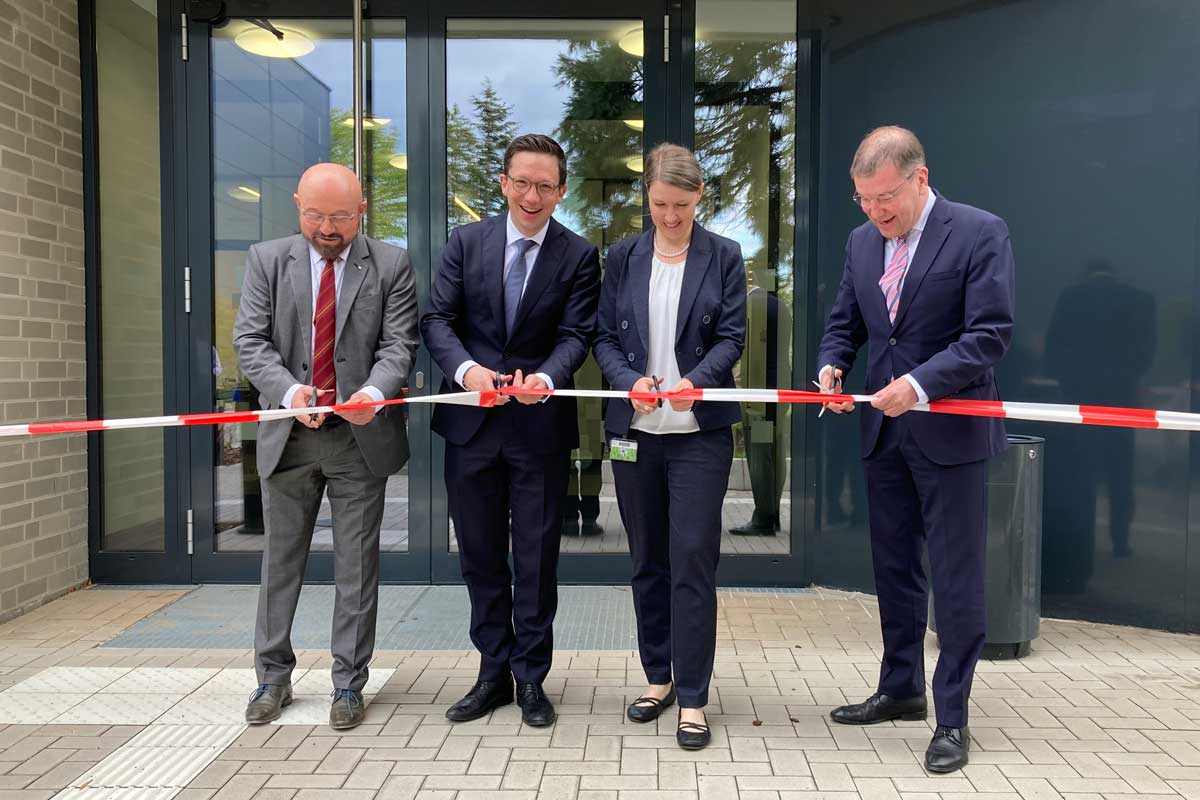 Einweihung des neuen Bürogebäudes am Campus Ahlem Das Foto zeigt vier Personen vor einem Hauseingang, die gerade ein Absperrband durchschneiden.