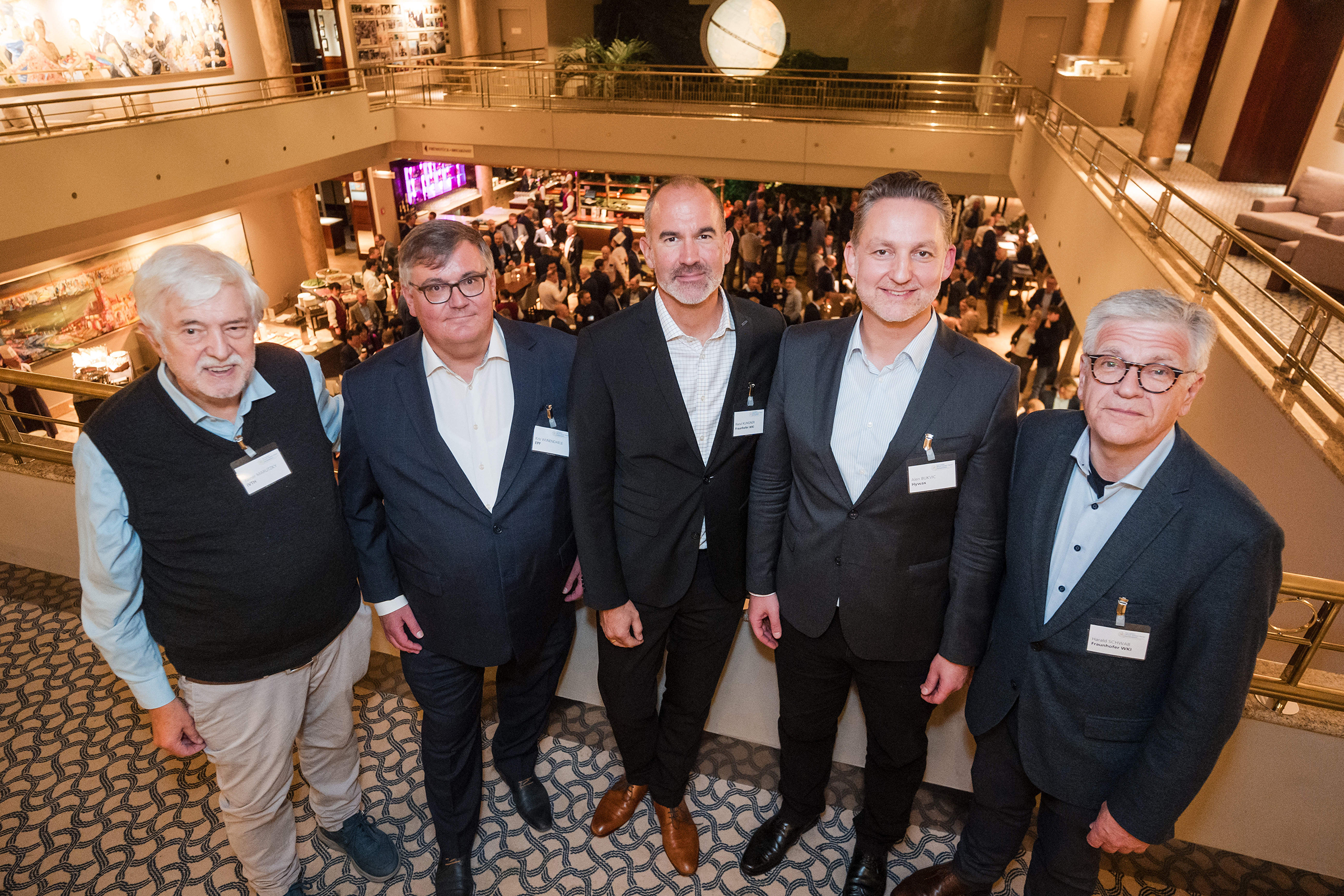 Eröffnung des 13. Europäischen Holzwerkstoff-Symposiums in Hamburg Das Foto zeigt eine Gruppe von fünf Männern in einem festlichen Tagungssaal voller Menschen.