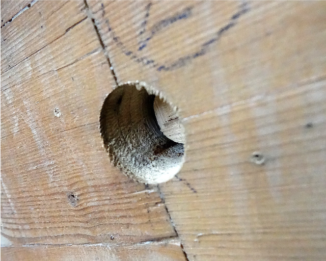 The photo shows two aged wooden beams that have been joined on the end grain side. An approximately 50 mm large and 30 mm deep hole was drilled in the area of the joint.
