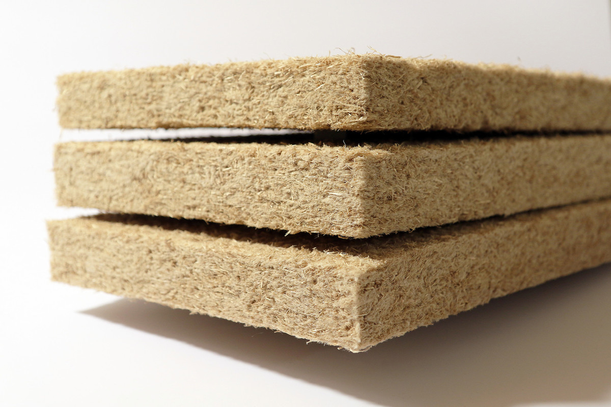 The photo shows a stack of insulation mats made from wood fibers. 