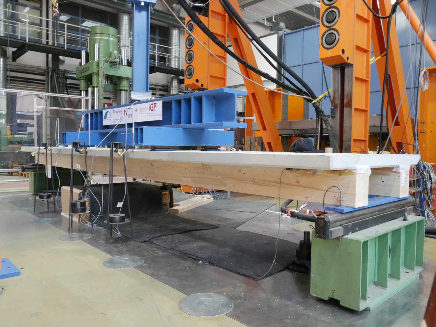 Test facility: rapid-bonding technology Hall with a large test facility made from steel in which a wood-concrete composite element is clamped. This consists of two horizontal wooden beams, spaced approximately half a meter apart, with a concrete slab bonded onto them.
