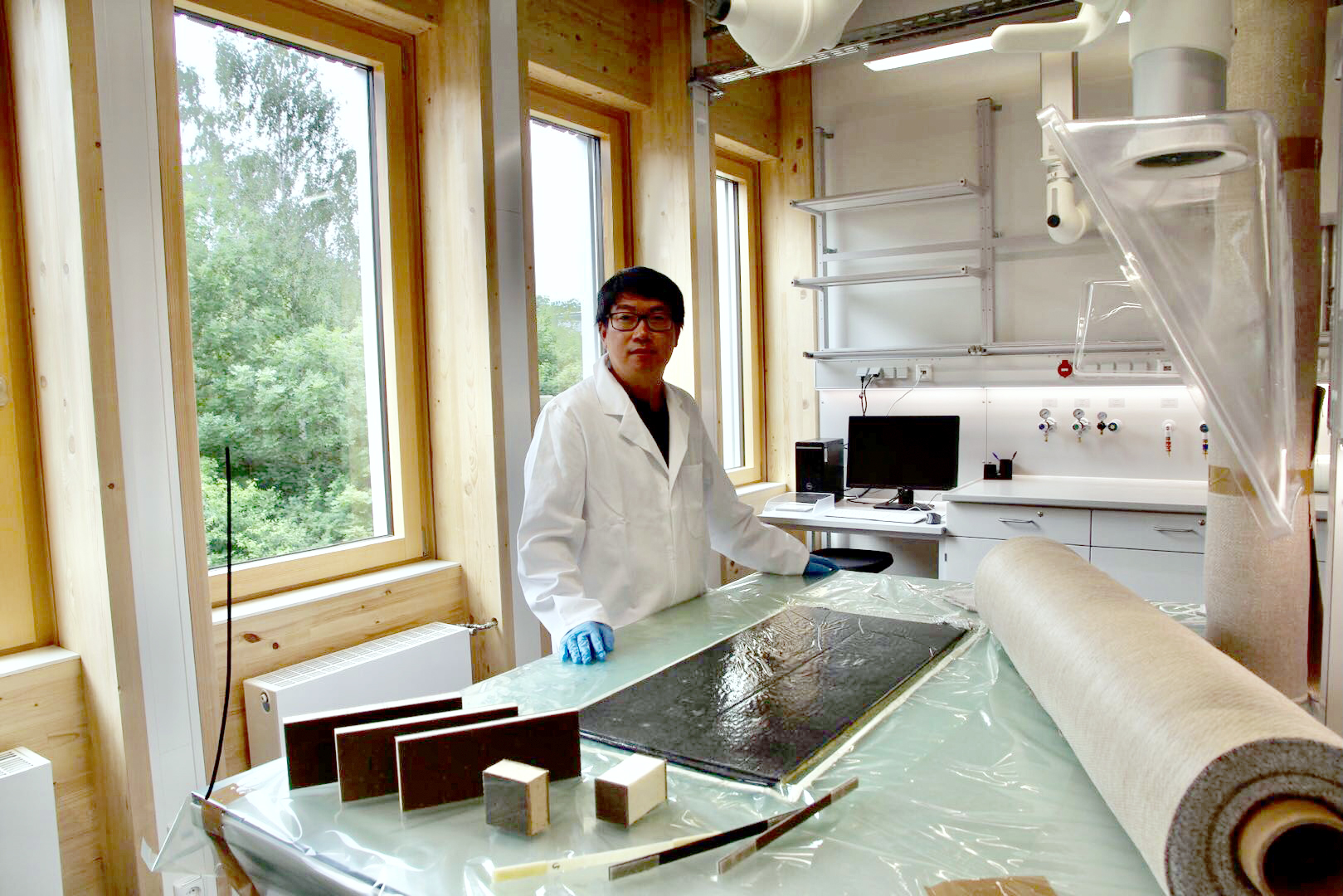 The photo shows Professor Yan at a laboratory table with various material samples.