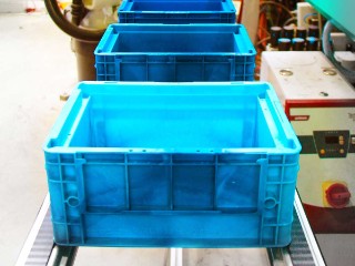 The photo shows three new transport boxes on a conveyor belt.