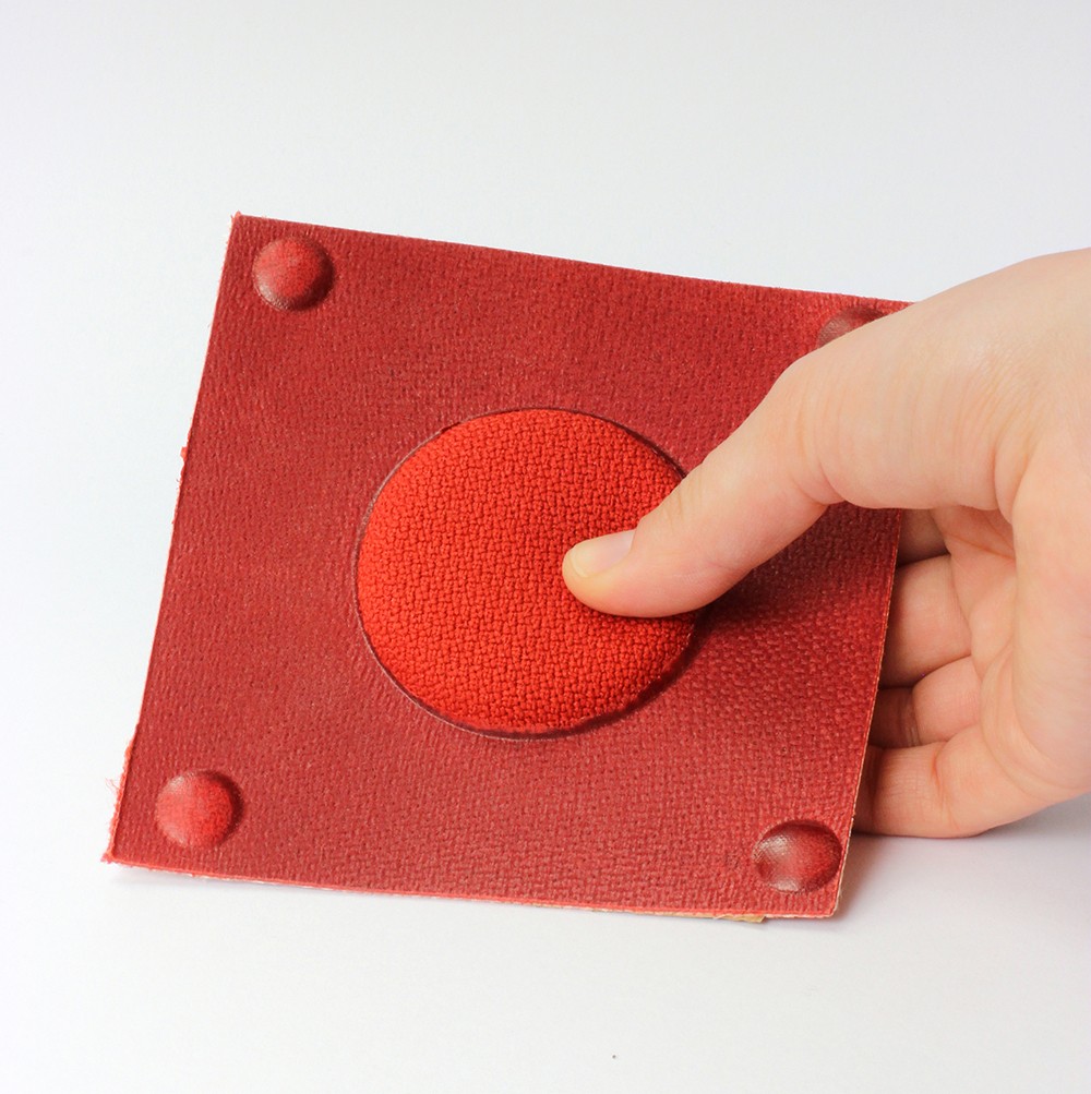 The photo shows a red organic sheet with a circular raised area that is padded.