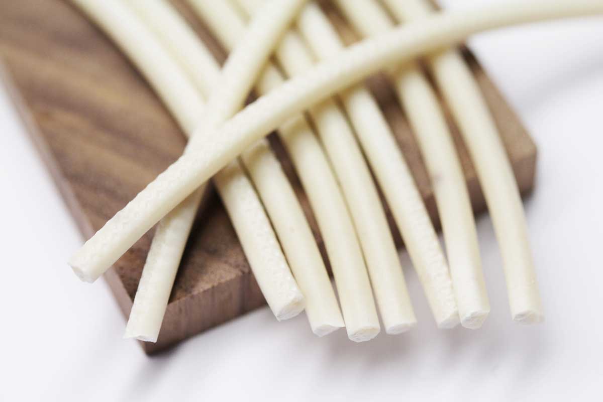 A bundle of white and brown filaments lies on a piece of wood.