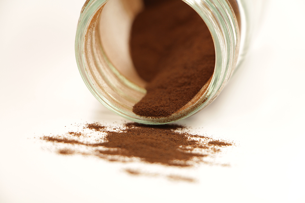 Laboratory glass without a lid, which contains a brown, coffee-like powder.