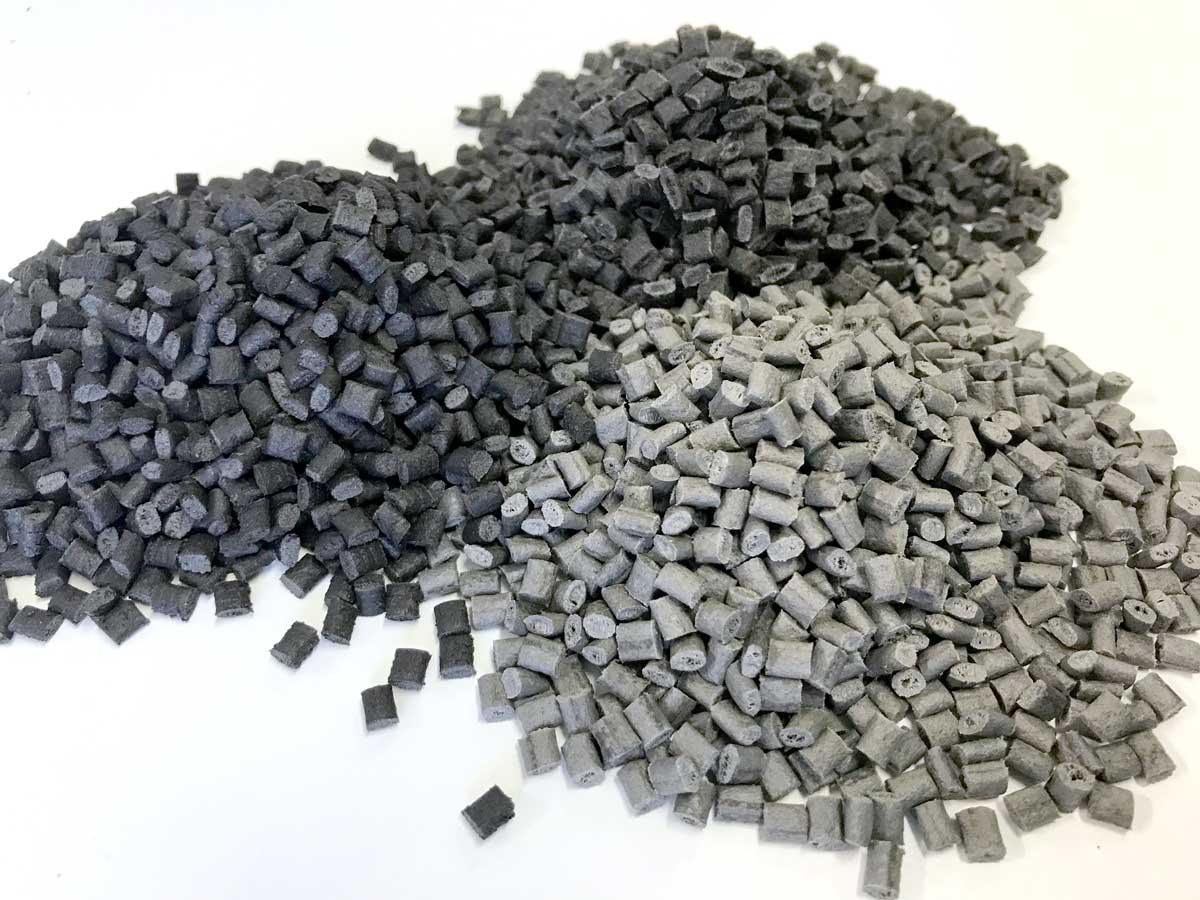 The photo shows three piles of small, cylindrical pieces (granules). One pile is black, one is medium gray, one is light gray.