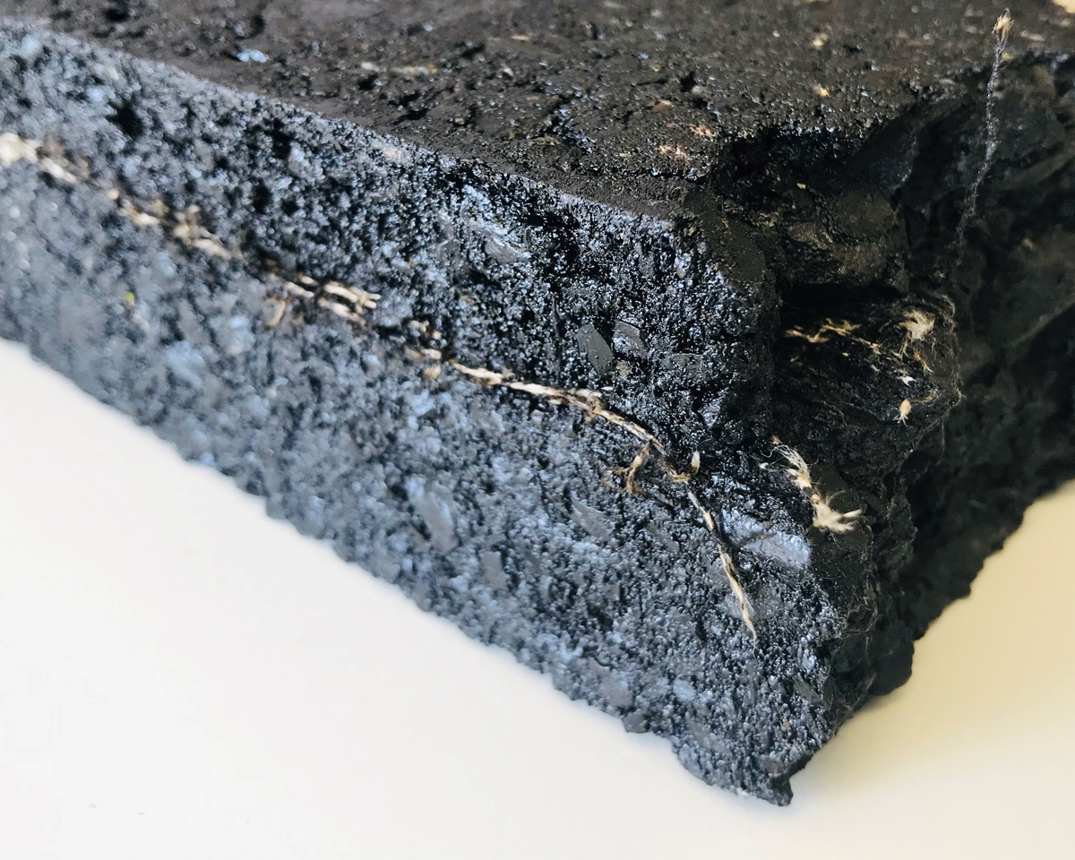 Cross-section of an asphalt test specimen with built-in sensor fabric which is visible at the cut edges. 
