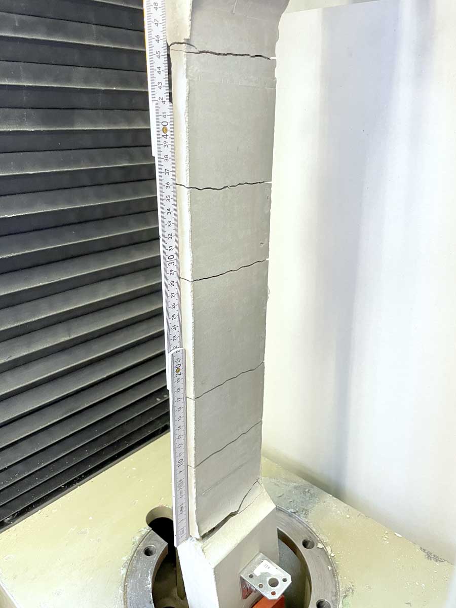 The photo shows an elongated concrete element which is clamped in an apparatus.