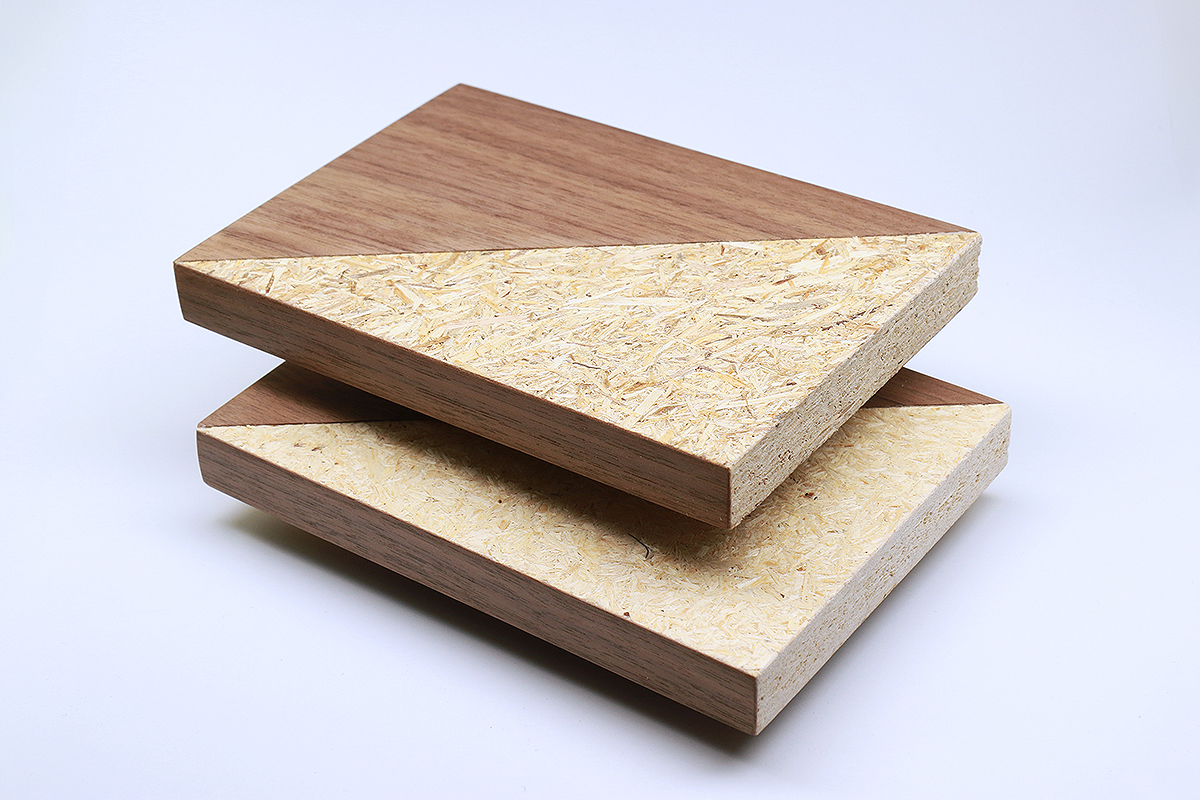 Waste wood particle board and fresh wood particle board The photo shows two partially veneered pieces of particle board that look almost identical. Some of the wood chips on the upper board are slightly darker.